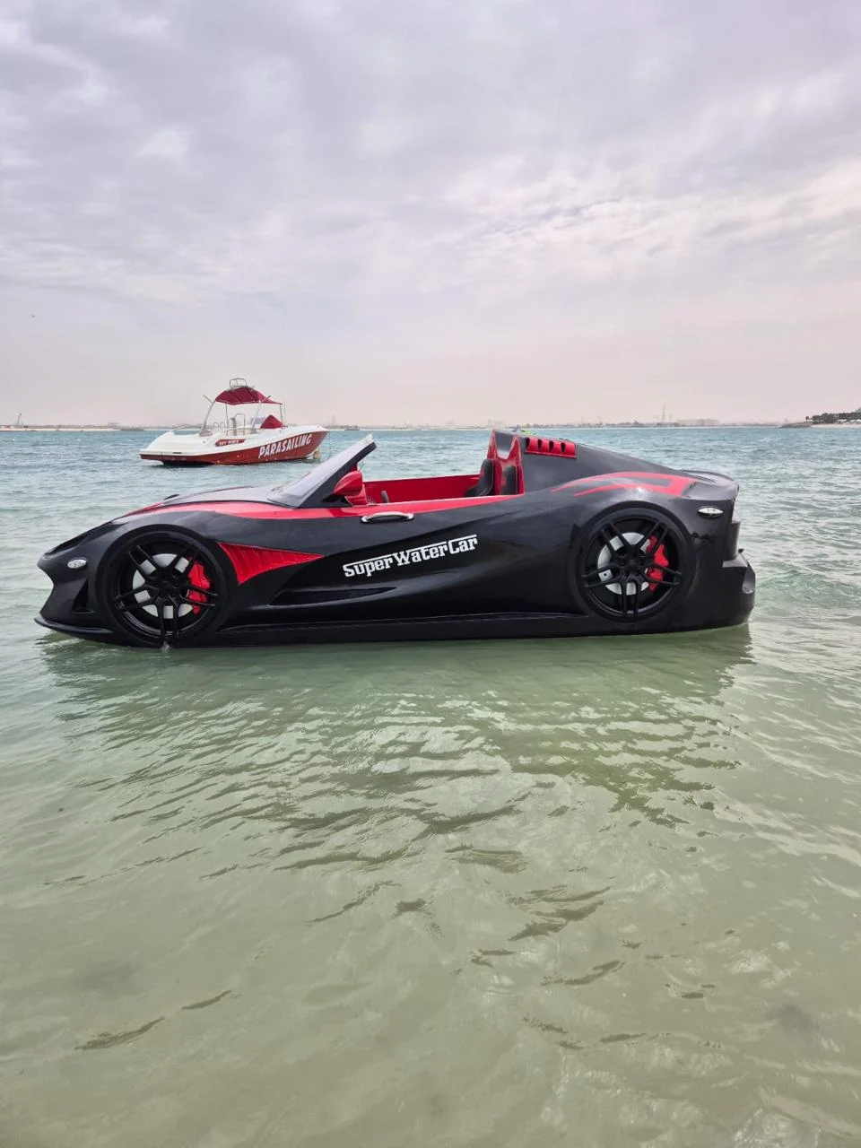 Black and red Super Water Car floating in shallow coastal water